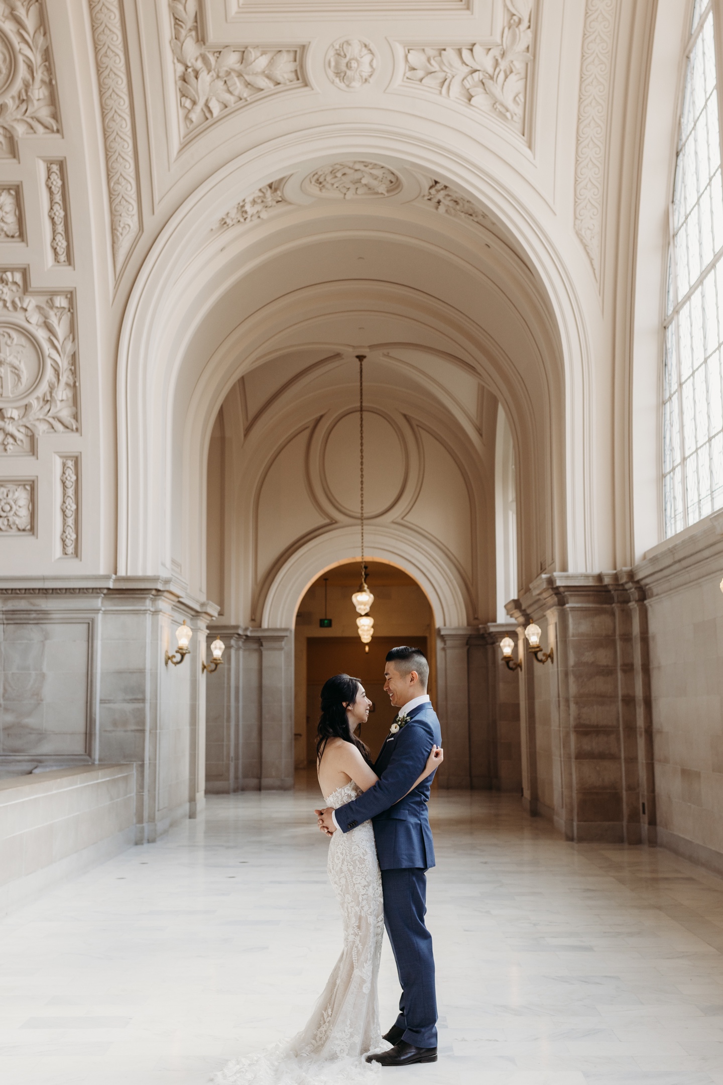 Bride and groom hug and gaze at each other in San Francisco City Hall after their elopement ceremony.