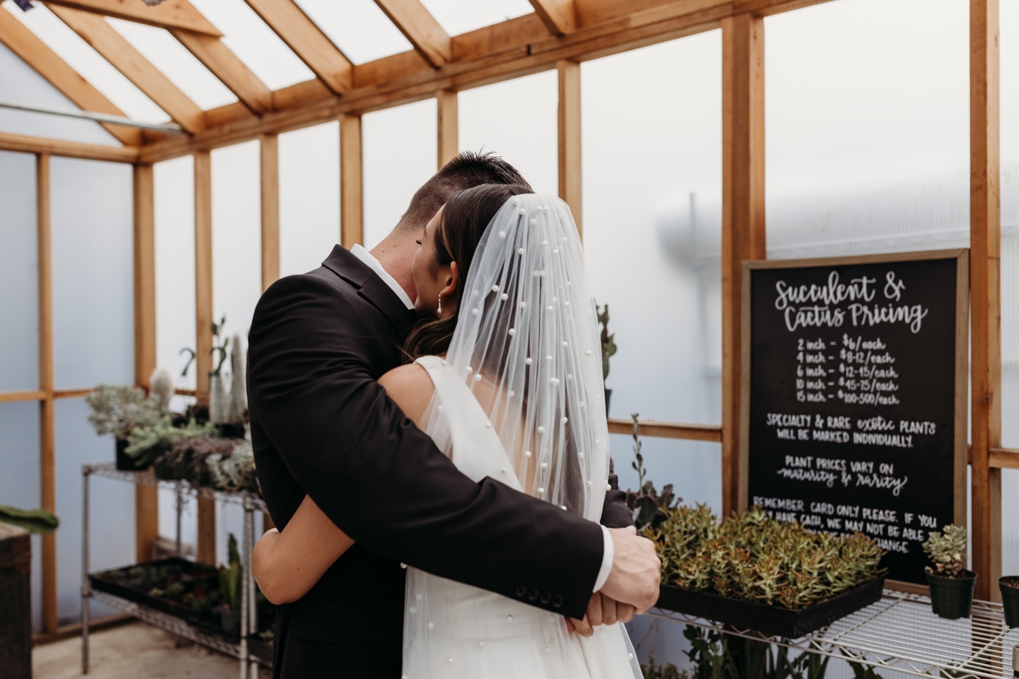 Bride and groom embrace in a greenhouse filled with succulents at the Prickly Pear in Sacramento, CA. 