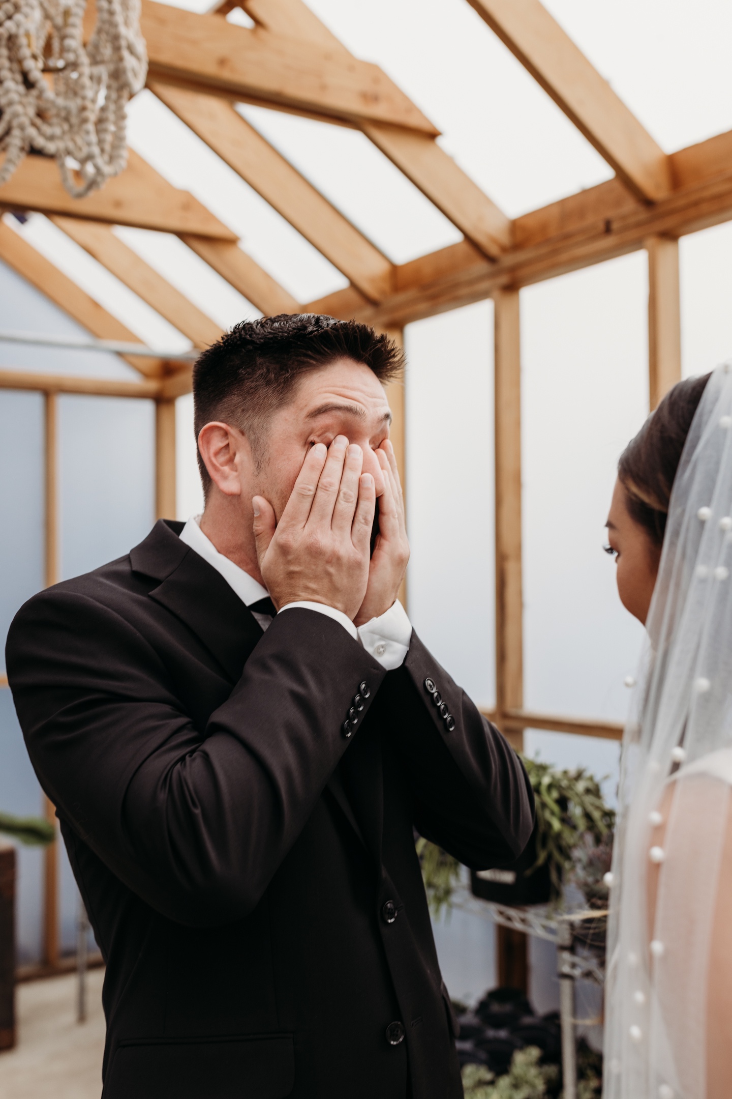 Groom covers his face and rubs tears from his eyes while looking at his bride. Liz Koston Photography.