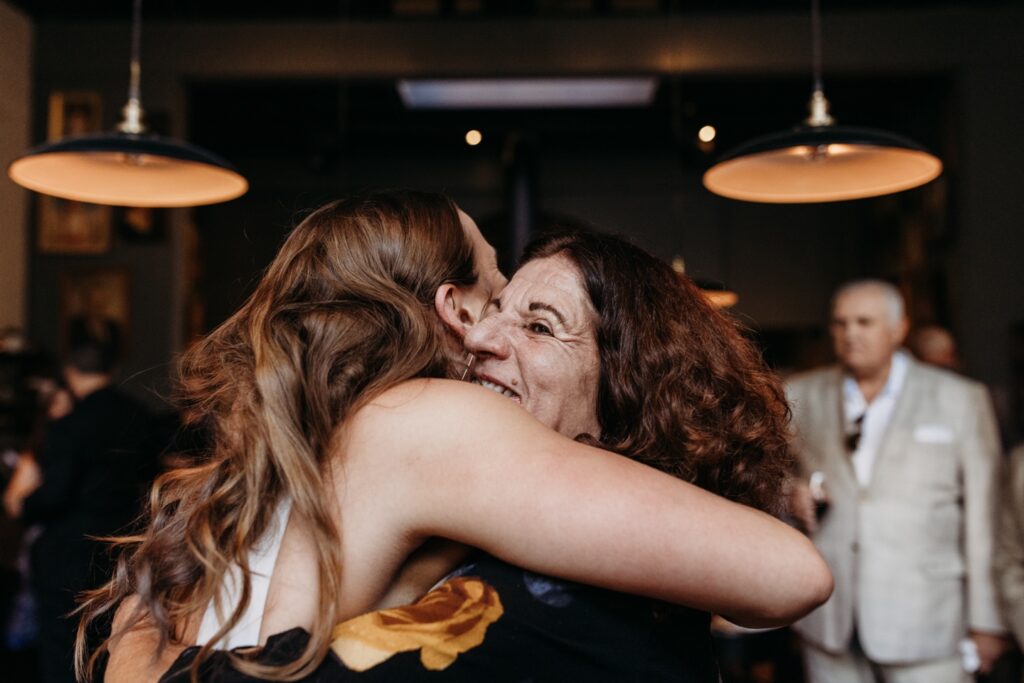 Bride hugs wedding guest at her wedding reception. Photo by Liz Koston Photography.