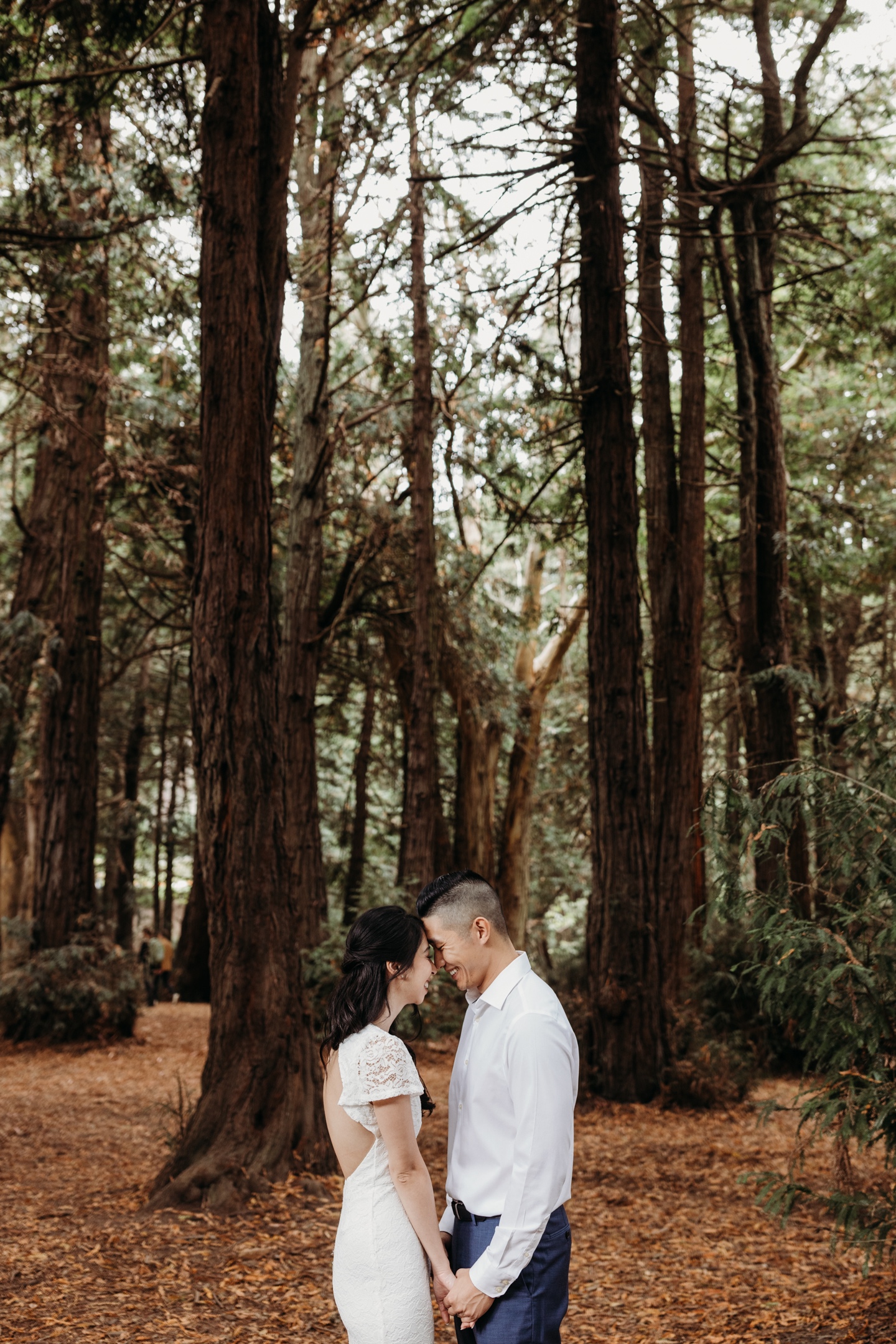 Bride and groom smile at each other while touching foreheads beneath the Redwoods in San Francisco's Golden Gate Park after their elopement.