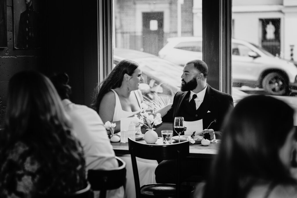 Bride and groom have an intimate conversation during their wedding reception dinner. Photo by Liz Koston Photography.