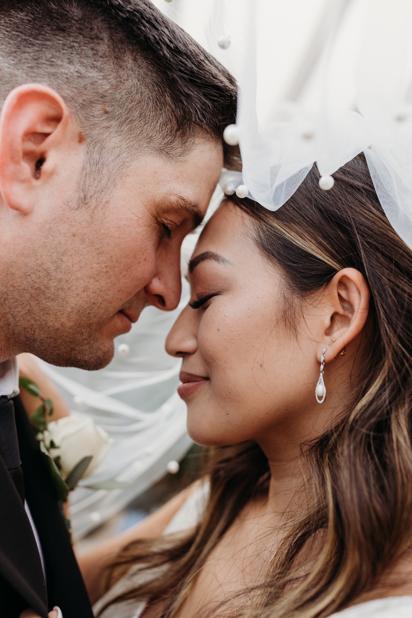Close up of the bride and groom touching foreheads beneath the bride's veil. Liz Koston Photography.
