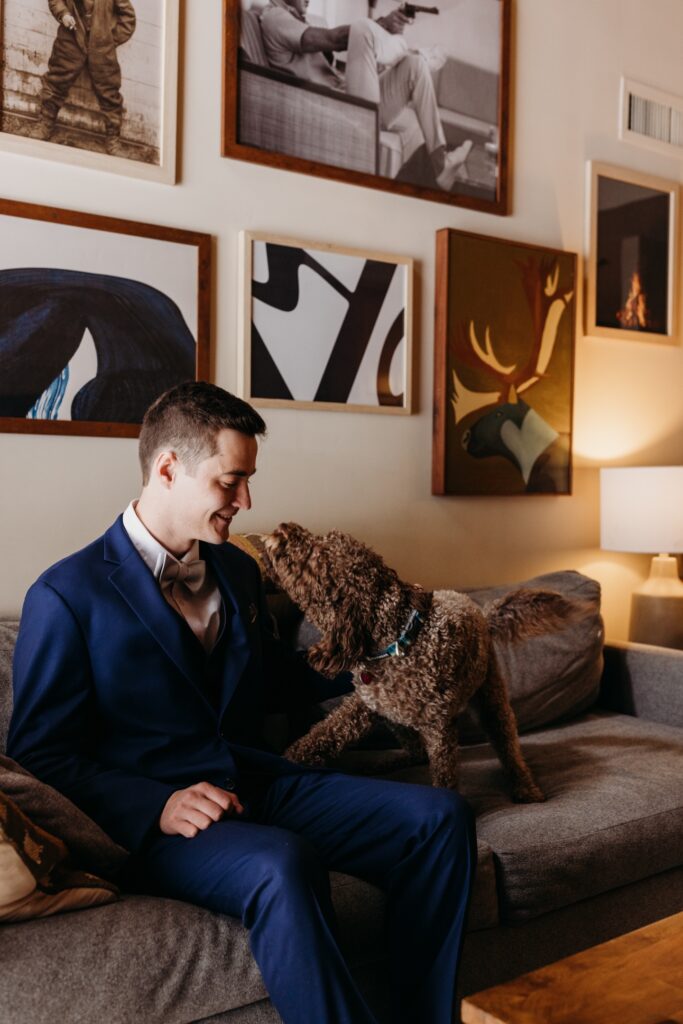 Groom plays with his dog on a couch in his Lake Tahoe apartment before his winter elopement. Liz Koston Photography.