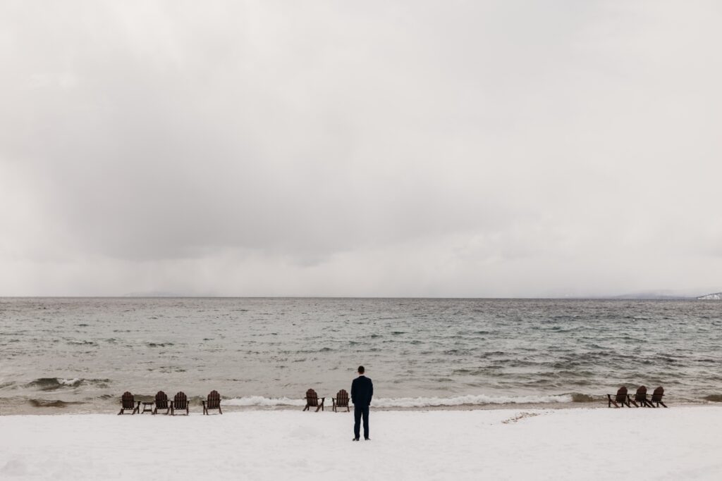 Groom stands in the snow looking out to Lake Tahoe. Liz Koston Photography.