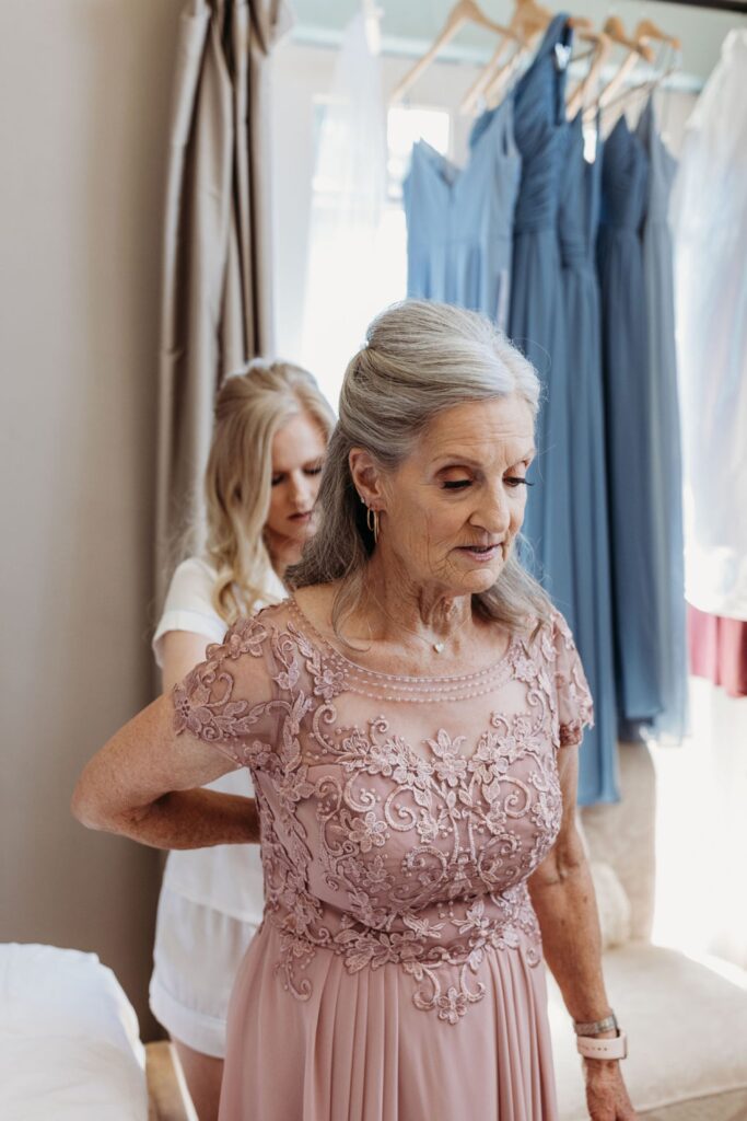 Mother of the bride getting dressed in her blush pink lace dress for her daughter's Helwig Winery wedding.