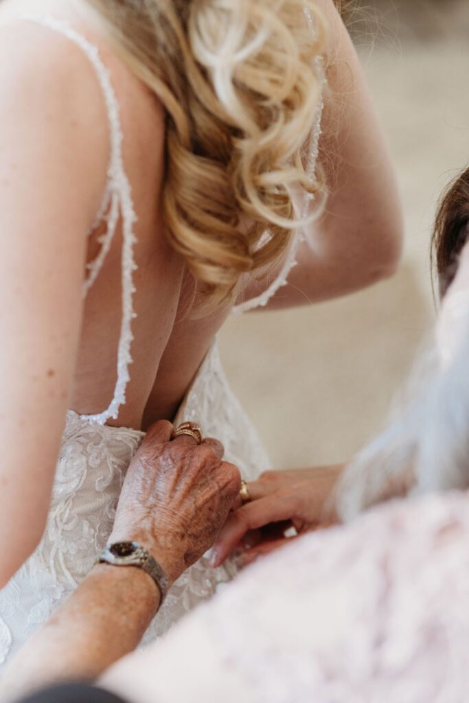 Mother of the Bride buttoning up her daughter's wedding gown for her Helwig Winery wedding. Liz Koston Photography.