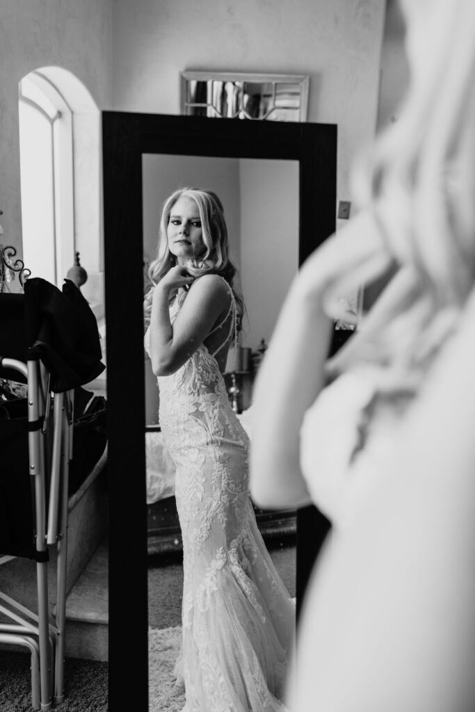 Bride looking at herself in the mirror in her wedding dress before her Helwig Winery wedding. Liz Koston Photography.