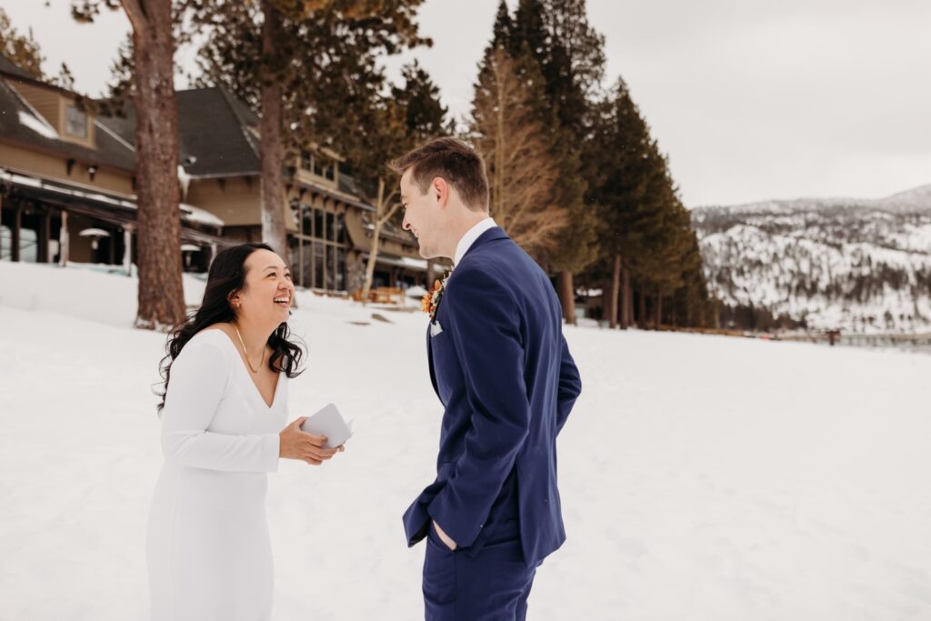 Bride reads her vows to her groom in a private moment before their Lake Tahoe winter elopement in the snow. Liz Koston Photography.
