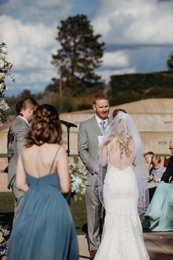 Bride reads her vows to the groom as he smiles at her. Liz Koston Photography.