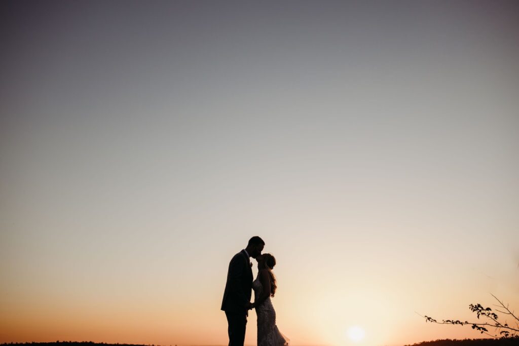 Bride and groom share a kiss as the sun sets over Helwig Winery. Liz Koston Photography.